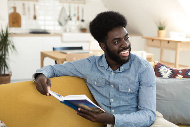 istock Young African American relaxing at home and reading a book 1486413672