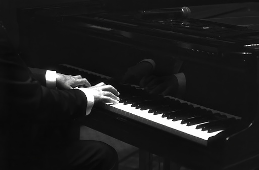 pianist is playing on a grand piano with reflections on the classic stylish instrument