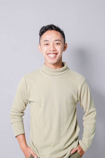 istock young asian man smiling confidently, isolated on gray background 1486416462