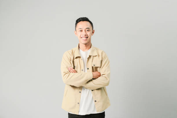 istock young asian man folding arms smiling confidently, isolated on gray background 1486417092