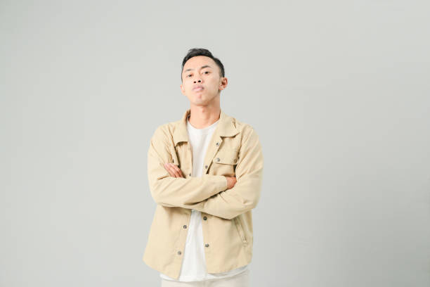 istock young asian man folding arms smiling confidently, isolated on gray background 1486417670
