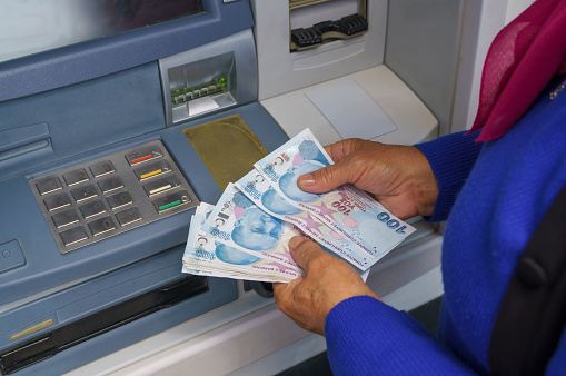 Senior woman holding Turkish Lira Bill Cash at Atm machine. Withdraw money