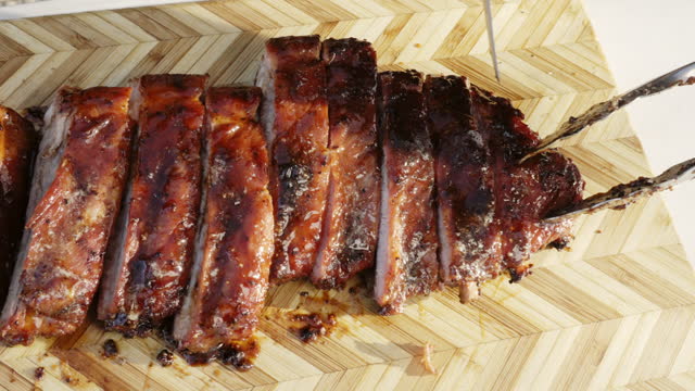 Slow-motion panning shot of barbecue pork spare ribs with sauce and seasoning, sliced and ready to serve