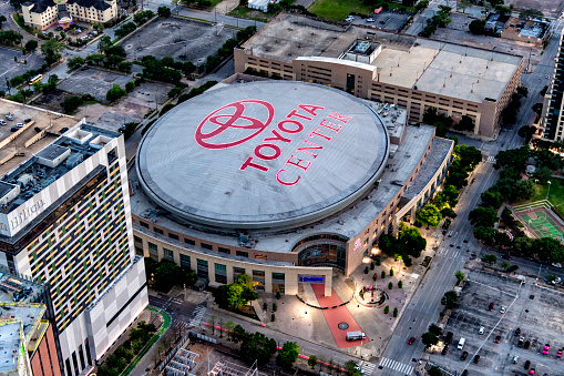 Houston, United States - April 13, 2023:  Aerial view of the Toyota Center, the home of the NBA's Houston Rockets; the sign illuminated at dusk, shot from about 600 feet in altitude from an orbiting helicopter.