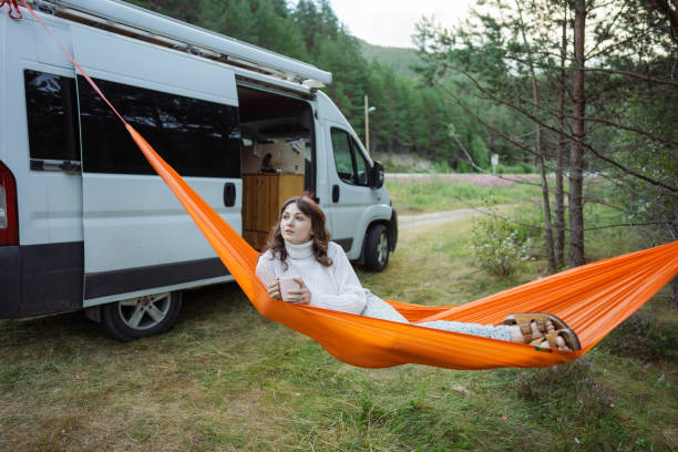 femme buvant du thé en se reposant dans un hamac près du camping-car - motor home park camping luxury photos et images de collection