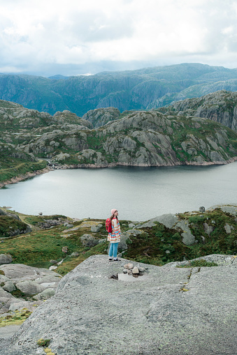 Young Caucasian woman with backpack hiking in Norwegian highlands