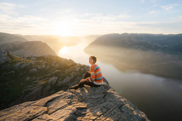 istock Woman sitting on Preikestolen and looking at view 1486450851