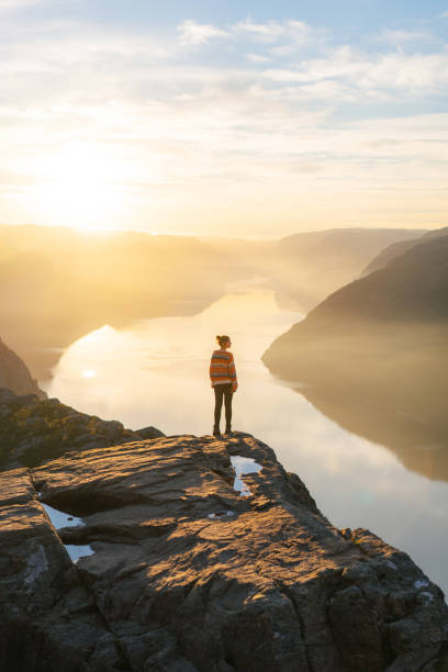 mulher em pé em preikestolen e olhando para a vista - fjord norway nature color image - fotografias e filmes do acervo