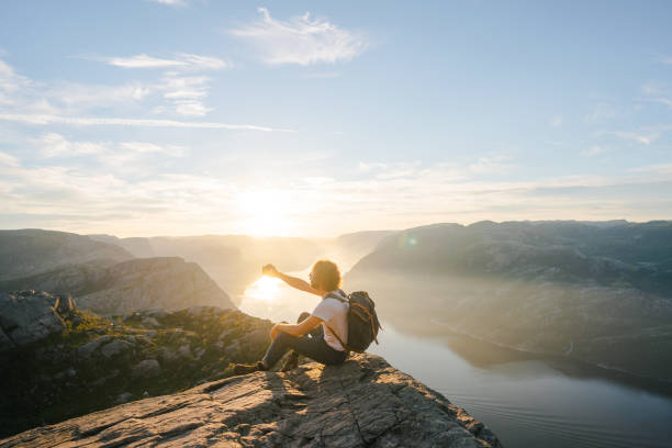 istock Man sitting on Preikestolen and making selfie 1486451061