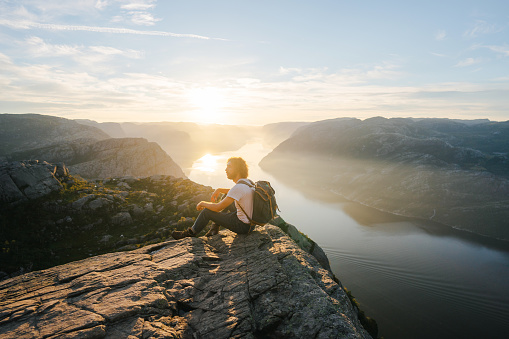 Caucasian man looking at scenic view of Lysefjorden from  Preikestolen at sunrise