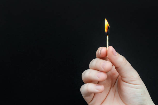 istock Hands holding burning match on black background. Copy space. 1486459008