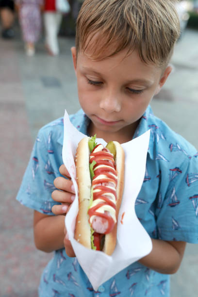 istock Boy with hot dog on street 1486460467