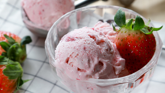 Closeup Strawberry ice cream in the glass cup with strawberry fruits background. Desserts summer season concept.