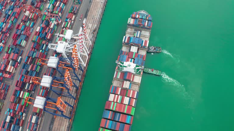 Aerial top view tug boat pulling container cargo ship park at loading dock in terminal commercial port and unload container with crane bridge, Business logistics import export shipping or freight transportation.