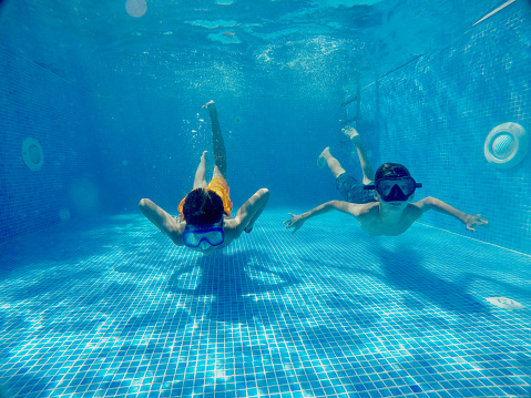 Teenage kids swimming underwater in the swimming pool