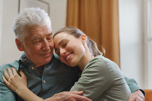 Young woman hugging her grandfather in the home.