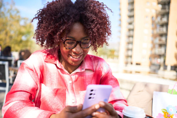 istock Young smiling latin woman with afro hair using mobile smart phone outdoors, using new trending technology apps. 1486474508