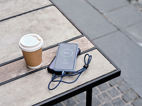 Charging a mobile phone with a power bank in a cafe, charge sharing concept