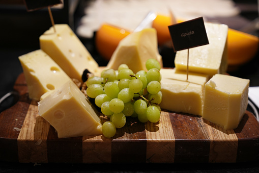 Cheese platter with different sorts of cheese and grapes on wood