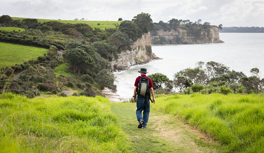 Man walking the Long Bay coastal walk. Auckland.