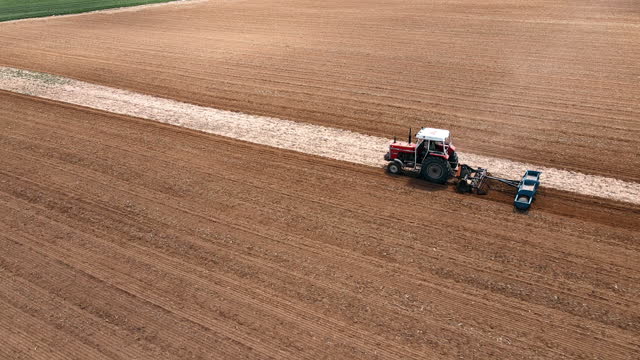 Preparing Fields for Planting: Seasonal Soil Cultivation from Above. Aerial view of tractor plowing a field