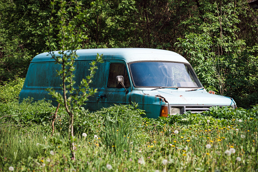 An old abandoned blue van in an open field