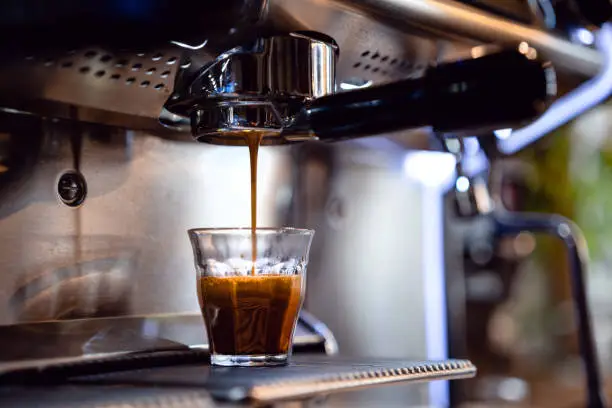 Espresso drops dripping from portafilter in small coffee shop