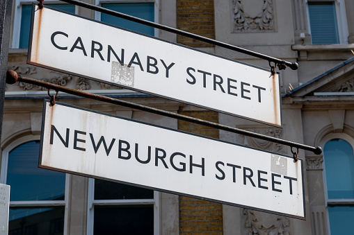 A sign for Carnaby Street and Newburgh Street. Famous tourist and shopping destination in Westminster, London, United Kingdom.