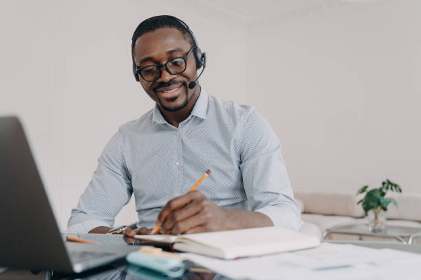 istock African american man in headset learns online at laptop, takes notes. Elearning, distance education 1486486747