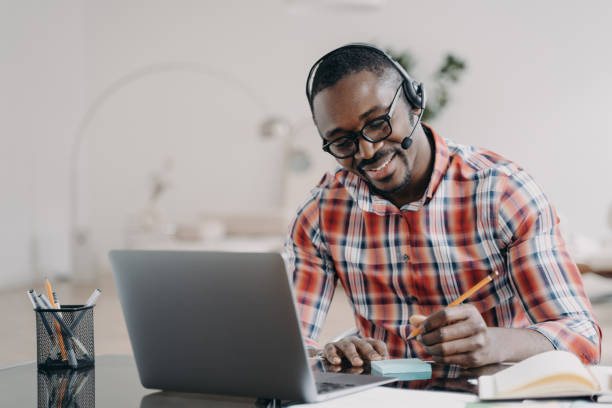 istock African american student in headset learning at laptop online, makes notes. Distance education 1486486777