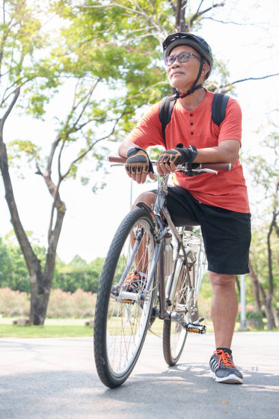 adulto mayor asiático montando en bicicleta en el parque - cycling senior adult sports helmet men fotografías e imágenes de stock