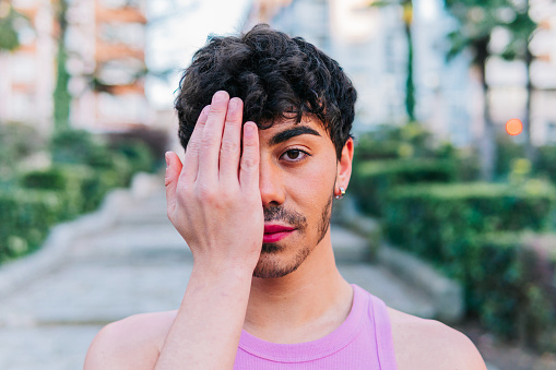 Man from the lgbt collective with makeup, covering his face with his hand in protest against homophobia.
