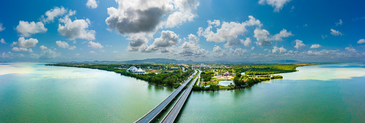 Bridge over water to green land of Songkhla aerial view on blue sky. panoramic landscape of transport.