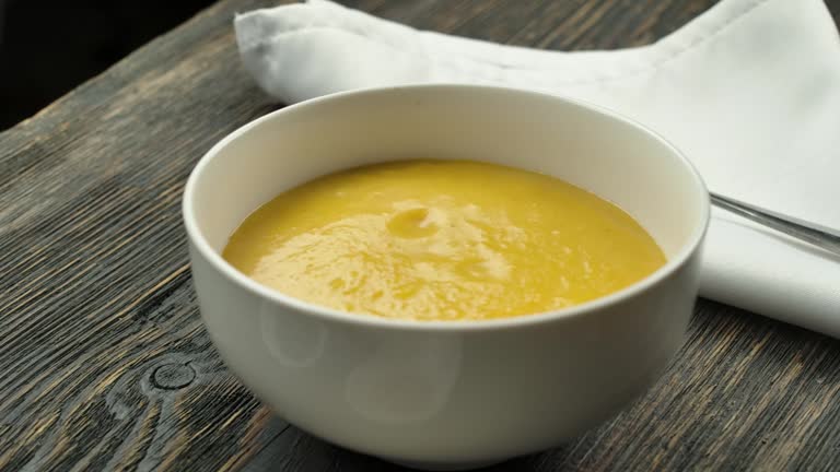 Pumpkin puree soup is poured into a plate with a ladle