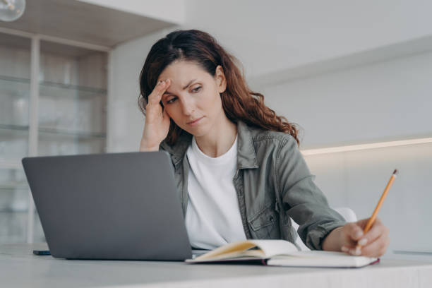 istock Overworked spanish lady has got a headache. Sick tired freelancer is working on laptop at home. 1486493336