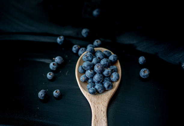 istock Fresh Blueberries in a wooden spoon on dark background 1486494127