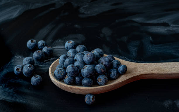 istock Fresh Blueberries in a wooden spoon on dark background 1486494128