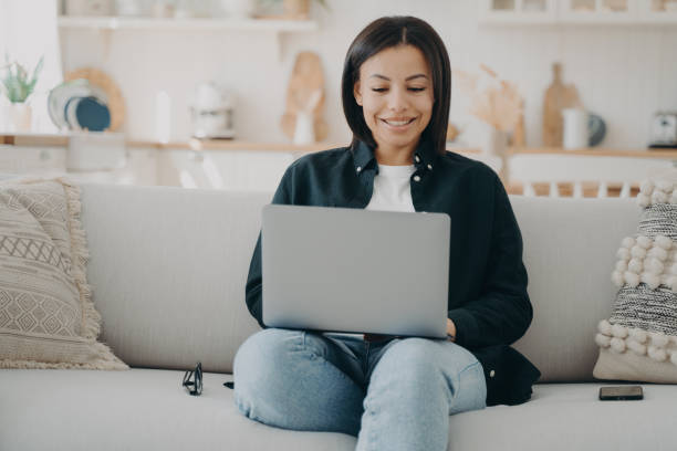 istock Happy girl typing on computer and smiling. Freelancer is sitting in comfortable couch with laptop. 1486494218