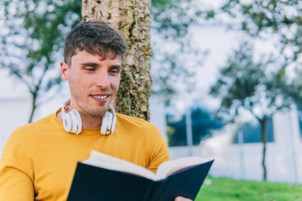 istock Cheerful man reading book in park 1486495604