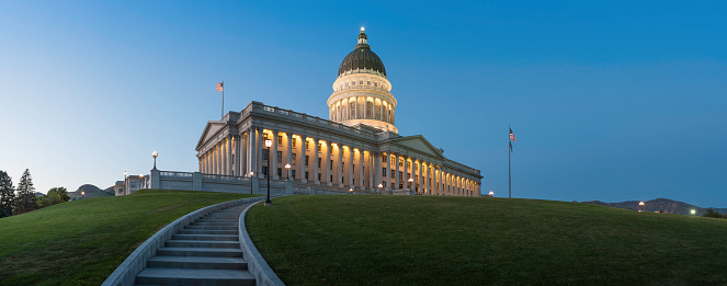 Path leading up the hill to the illuminated Corinthian columns and magnificent Neoclassical dome of the Utah State Capitol glowing against deep blue dusk skies high above Salt Lake City, USA. ProPhoto RGB profile for maximum color fidelity and gamut.