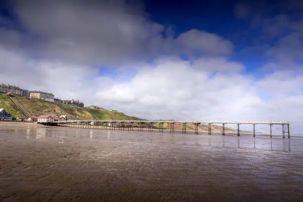 The old Victorian pier at Saltburn stretching out over the beach at low tide.