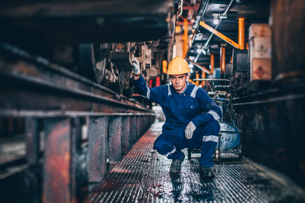 porträt kaukasischer männlicher arbeiter bei der arbeit in lokomotivreparaturwerkstätten glücklich lächelnd - schwerindustrie stock-fotos und bilder