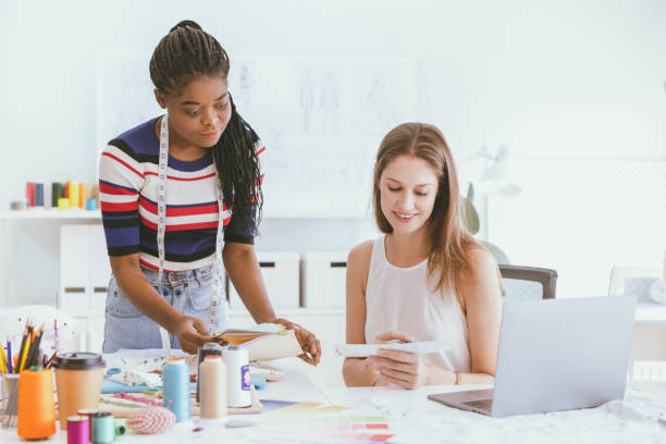 istock Tailor dressmaker talking together to select color and type of textile process for new fashion clothes dress cutting. 1486501332