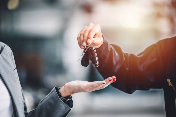 Closeup male hand giving a car key for vehicle loan credit financial, lease or rental concept stock photo