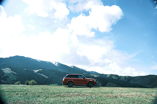 Jeti-Oguz, Kyrgyzstan - April 30, 2023: red Range Rover is standing on high plane against the mountain peaks