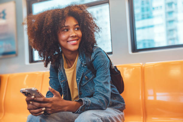 feliz jovem afro-americano mulher passageiro sorriso e usando o telefone móvel inteligente na estação de trem do metrô - public transportation - fotografias e filmes do acervo