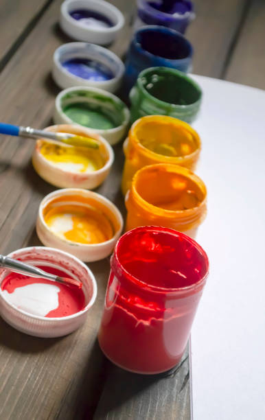 istock Colored paints in jars on a wooden table. Paints for drawing different colors. Colored paints of the LGBT community or rainbow on the table. 1486521713
