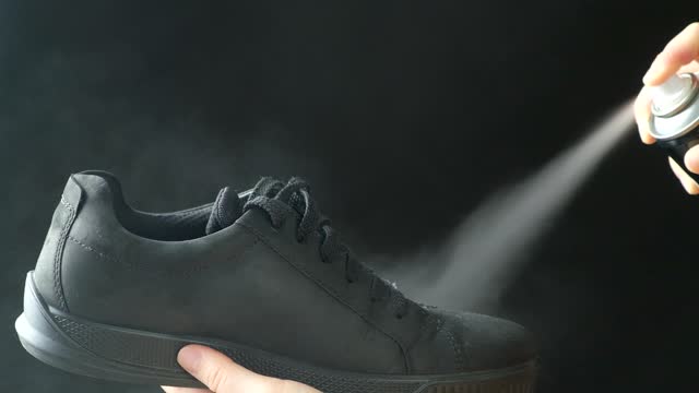 The process of applying a water-repellent spray to black men's nubuck demi-season shoes