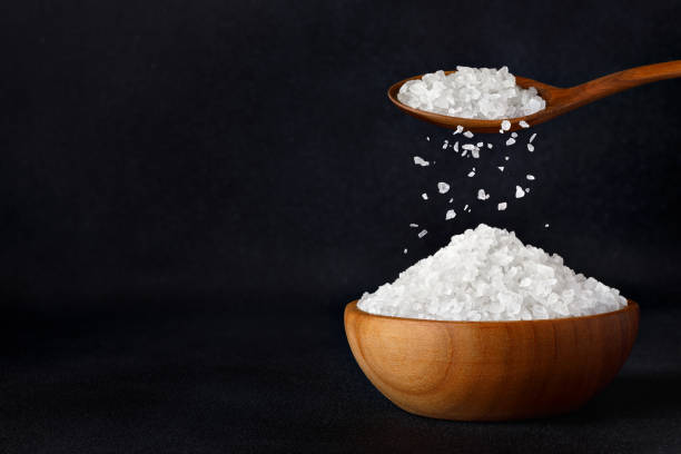 istock sea salt crystals falling from spoon in bowl on black background 1486524389