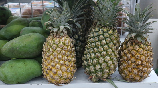 Pineapples and mangoes are sold in mini markets and placed on shelves.